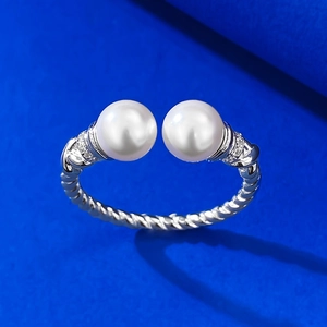 Macro view of twisted silver band ring featuring dual white pearls and zircon accents