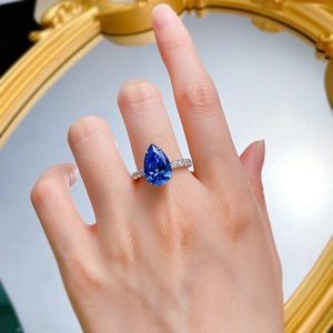 Dettaglio di un anello con zaffiro blu reale a goccia e fascia pavé sulla mano di una modella