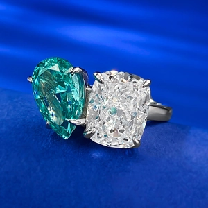 Macro shot of Toi et Moi ring featuring pear-cut green and cushion-cut white stones
