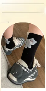 Detail of black mid-calf cotton socks with cartoon cat pattern and 3D pom-pom accents