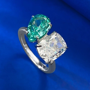 Macro detail of Toi et Moi ring with pear-cut emerald and cushion-cut white stone
