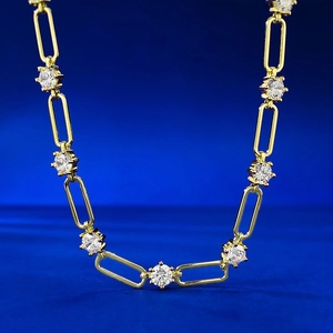 Collana a graffetta dorata con cristalli rotondi su uno sfondo blu scuro intenso