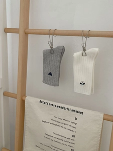 Detailaufnahme von gerippten Baumwollsocken mit Herz- und Welpen-Stickerei am Bündchen