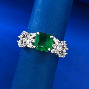 Gros plan détaillé d'une bague avec émeraude carrée et amas de diamants sur les côtés