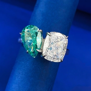 Toi et Moi ring featuring pear-cut green and cushion-cut white gemstones on a silver band
