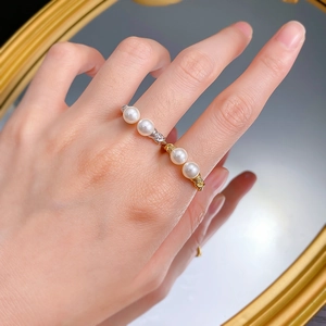 Close-up of four stackable gold and silver rings with white pearls on a twisted metal band