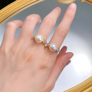 Detailed view of silver and gold rings with 10mm pearls and pavé set small diamonds