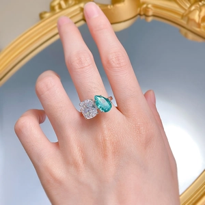 Close-up of double-stone ring with pear-cut Paraiba and cushion-cut carbon diamond on finger
