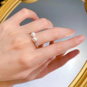 Close-up of dual pearl ring with textured silver rope band worn on finger