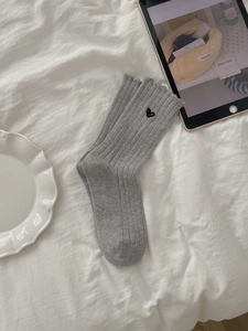 Detailansicht grauer Rippstrick-Socken mit kleinem dunkelblau besticktem Herzdekor