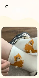 Detail of white cotton sock featuring 3D plush orange tabby cat paw decorations