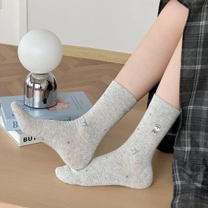 Gros plan de chaussettes mi-hautes gris clair à pois bleus avec broderie de chien mignon