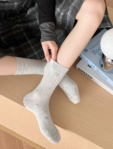 Détail de chaussettes en coton gris clair avec pois bleus et broderie nœud mignon