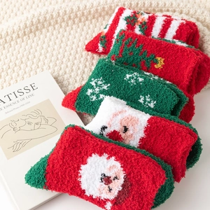 Five-pack Christmas fuzzy socks with festive red and green patterns on cozy knit blanket