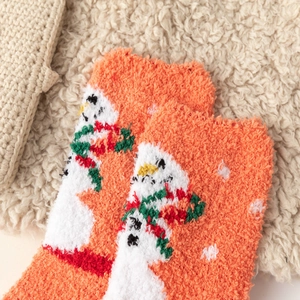 Close-up of thick orange coral fleece winter socks with white snowman pattern texture