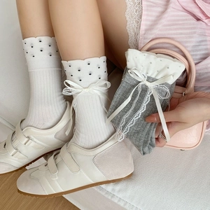Detail of polka dot ruffle socks with white lace bows and wavy edges in a set