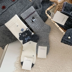 Détails de chaussettes en laine avec motifs de chat et tricot gris ambiance cosy