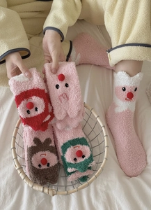 Close-up of pink coral fleece socks with cute cartoon embroidery in a cozy home setting