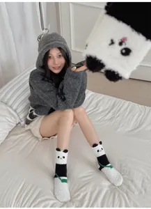 Gros plan de chaussettes panda en polaire corail et sweat à capuche assorti chez soi