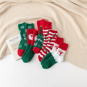 Detail of assorted Christmas coral fleece socks with festive patterns on a cozy knit background