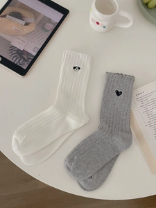 Details von japanischen Baumwollsocken mit Panda- und Herzstickerei auf weißem Tisch