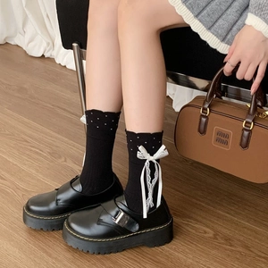 Close-up of black high-elastic cotton mid-calf socks with white lace bows and wavy cuffs