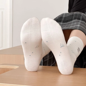 Détail de chaussettes en coton blanc avec broderie d'animaux mignons et motifs de nœuds bleus