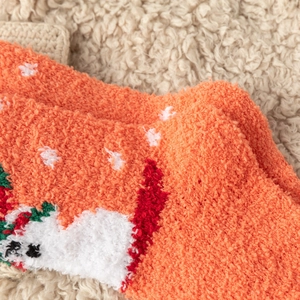 Close-up of thick orange coral fleece Christmas socks with festive winter patterns
