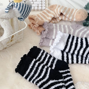 Detail of coral fleece striped socks with ruffled cuffs on a cozy white rug