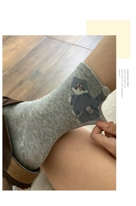 Close-up of gray cotton crew socks featuring 3D blue cat pattern and plush pom pom ball