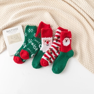 Close-up of four pairs of thick coral fleece Christmas socks with festive embroidery