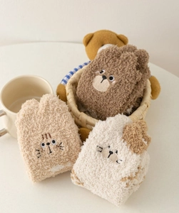 Close-up of three pairs of fluffy coral fleece socks with cute cartoon animal embroidery