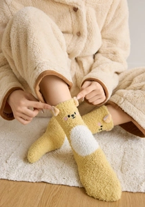 Détail de chaussettes en polaire corail jaune avec oreilles d'ours 3D et broderie