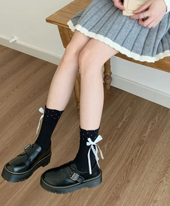 Polka dot socks with white lace bows paired with black Mary Jane shoes and a pleated skirt