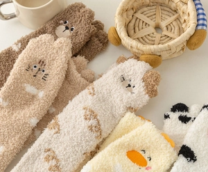 Close-up of cozy coral fleece socks with cute cartoon animal embroidery and plush texture