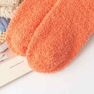 Close-up of thick orange chenille fuzzy socks with warm and soft coral fleece texture