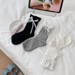 Detailed knit texture of mid-calf socks with lace trim and satin bow accents
