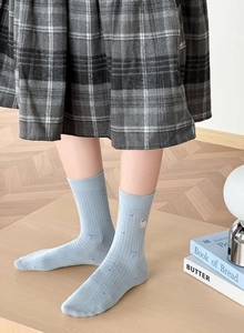 Détail de chaussettes mi-hautes bleu clair à côtes avec broderie de mouton mignon