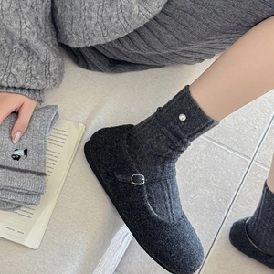 Détail de chaussettes en laine Fair Isle grises avec broderie chat et perle