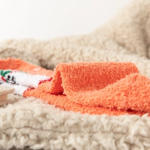 Macro detail of thick orange coral fleece socks with festive winter jacquard pattern