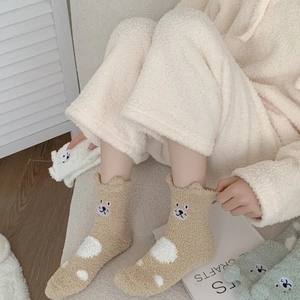 Detailed macro view of coral fleece socks featuring 3D bear ears and cute paw embroidery