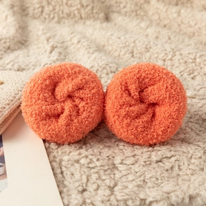 Detail view of vibrant orange coral fleece wristbands with soft fluffy texture on plush fabric