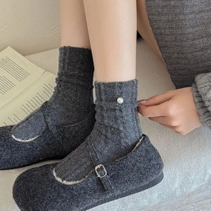 Détail de chaussettes en laine gris foncé avec perles et chaussons Mary Jane en peluche