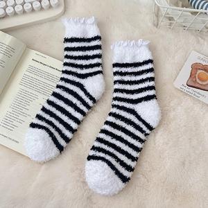 Detailed view of striped coral fleece socks with ruffled edges on a cozy background