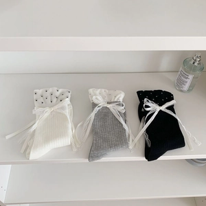Detail of knit socks with polka dot chiffon ruffles and lace bows in white, grey, and black
