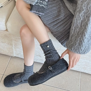 Détail de chaussures Mary Jane gris foncé avec chaussettes à perle sur pierre