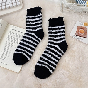 Detail of black and white striped coral fleece socks with delicate ruffled cuffs on soft rug