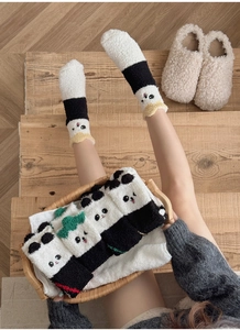 Gros plan de chaussettes en polaire corail panda 3D présentées sur un escalier en bois