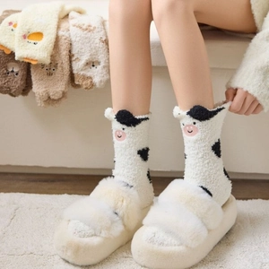 Close-up of coral fleece socks with cute cow pattern and thick plush indoor slippers
