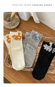 Detailed close-up of cute cat socks with 3D plush tails in a rustic wicker basket